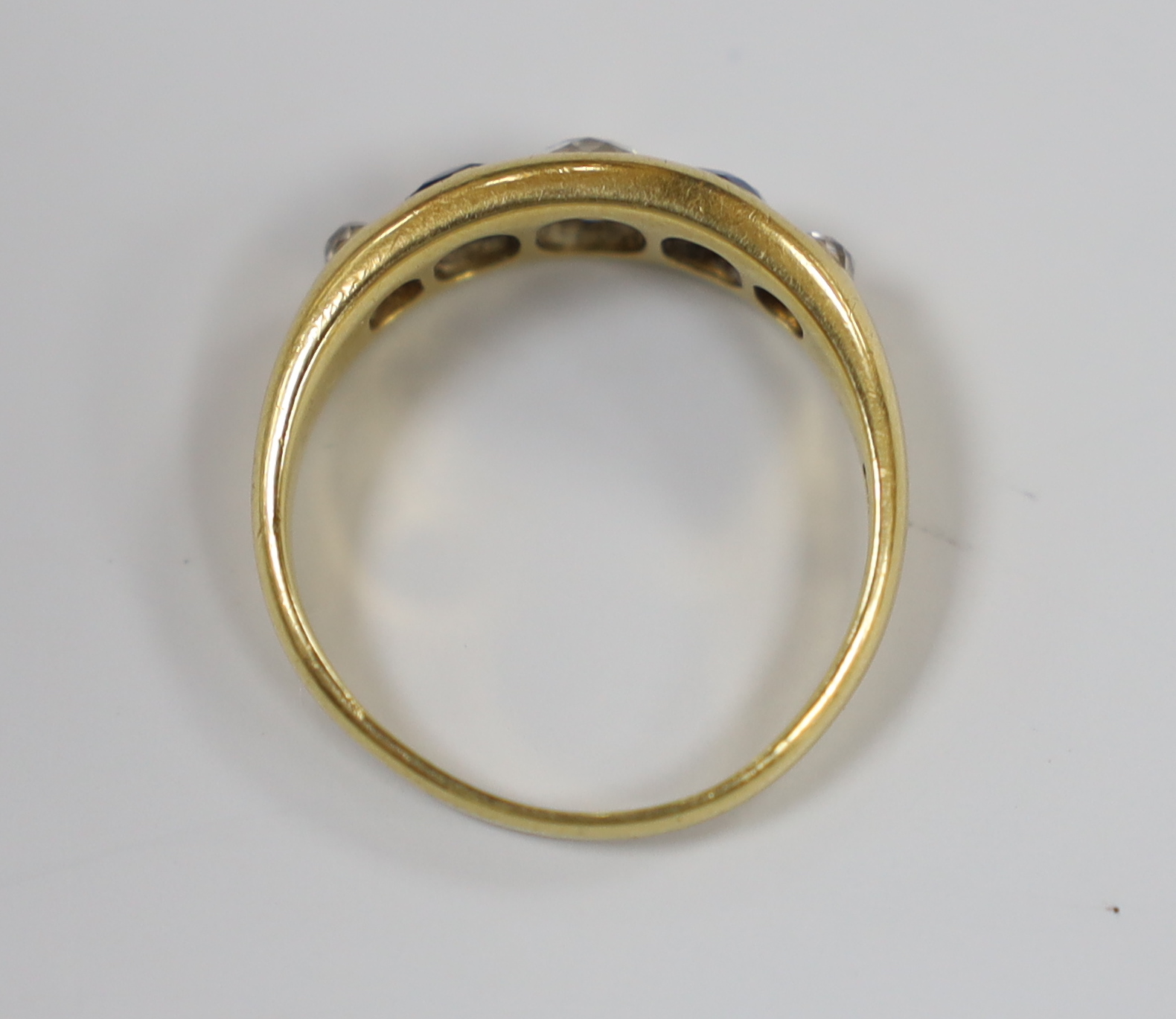 A yellow metal and gypsy set three stone diamond and two stone sapphire set half hoop ring, size S/T, gross weight 5.6 grams.